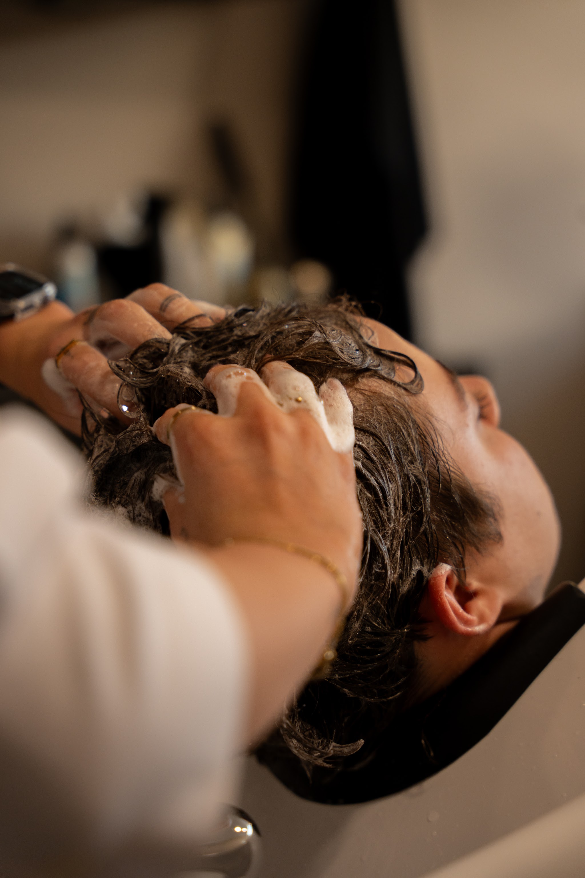 Haren wassen aan de wasbak, handen die het haar van een klant masseren